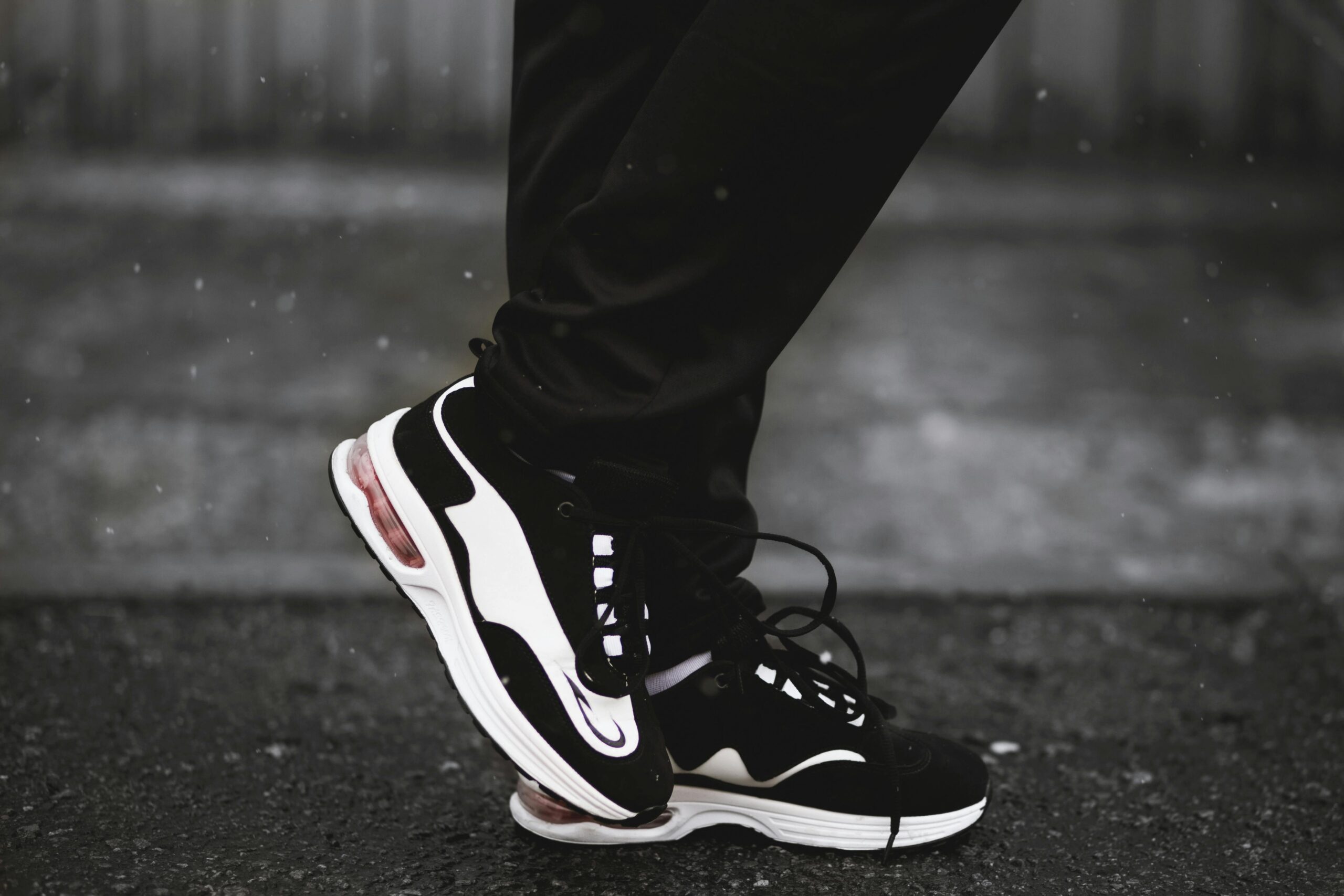About Close-up of black and white sneakers worn by a runner on a rainy street, perfect for sportswear.